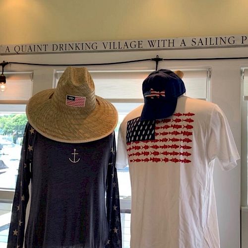 Two mannequins dressed in nautical-themed clothing and hats stand under a sign that reads "A QUAINT DRINKING VILLAGE WITH A SAILING P".